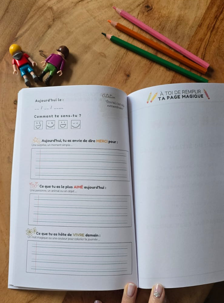 Carnet de Joies Yorokobi Journeys posé sur une table avec crayons, outil ludique pour cultiver la joie et la confiance en soi chez l’enfant